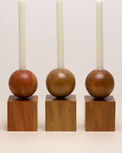 Load image into Gallery viewer, Three Hand-carved candle holder made from kauri and Tōtara wood, featuring a spherical base atop a square block.