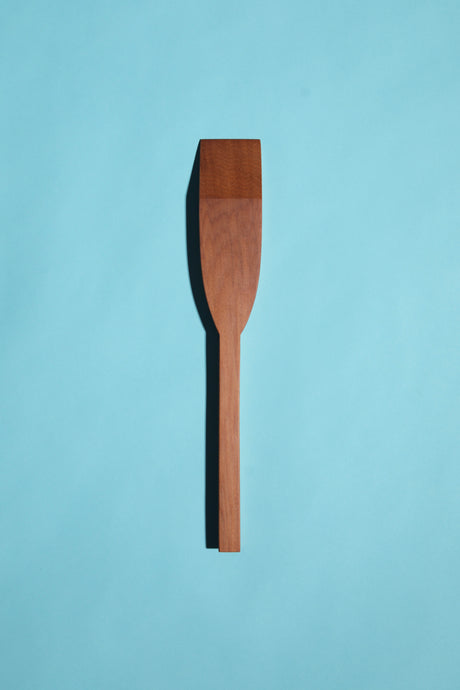 hand-made mataī mini spatulas with square handles and mitred tips, on a blue background.”
