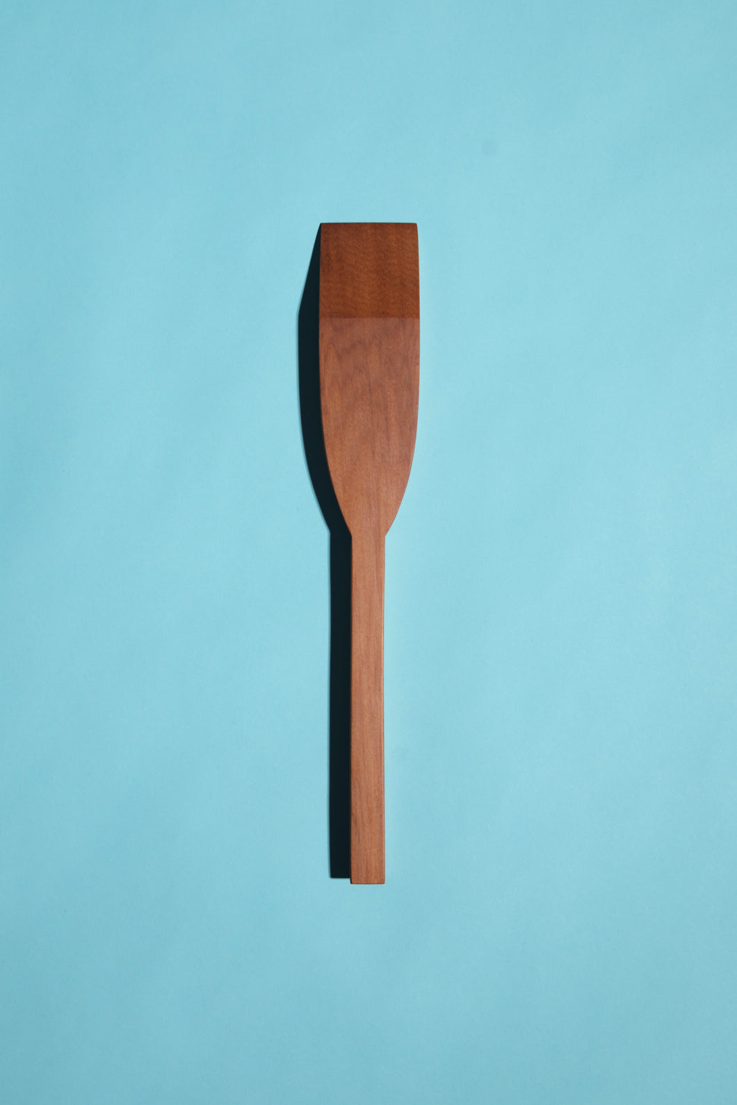 hand-made mataī mini spatulas with square handles and mitred tips, on a blue background.”
