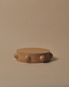 A round Kauri chopping or cheese board with 7 half spheres carved and placed equally around the outside edge