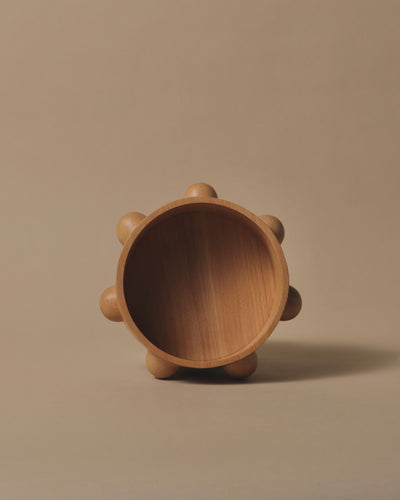 Round Kauri bowl with a flat base with 7x half spheres carved in equal distance around the edge of the bowl.