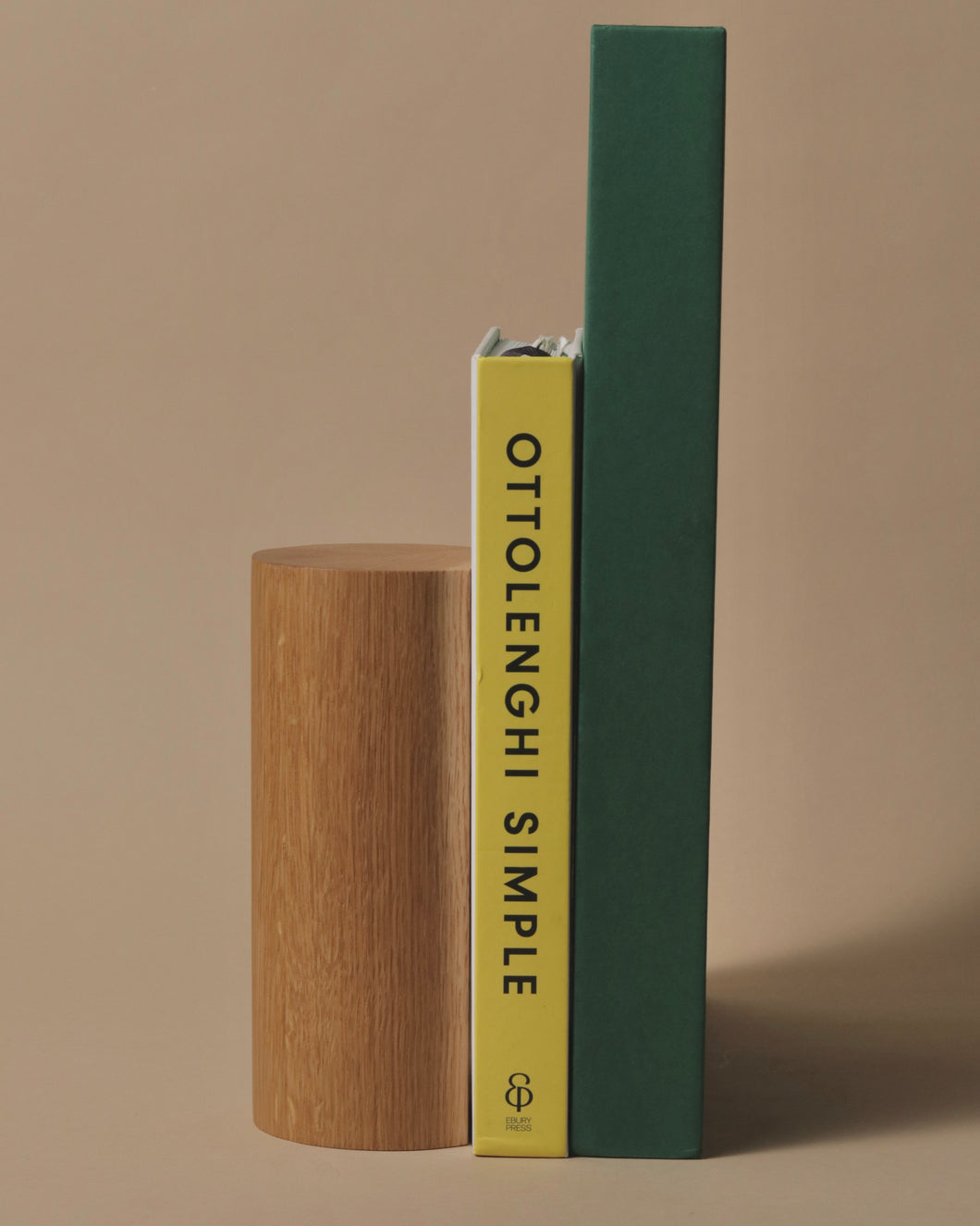 Handcrafted oak bookend holding two books, including 'Ottolenghi Simple,' showcasing a minimalist and elegant design.