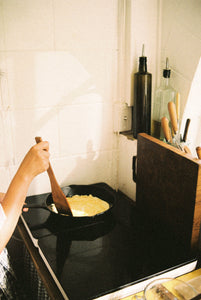 A hand made wooden spatula made from native New Zealand timbers flipping an omelette in a cast iron pan