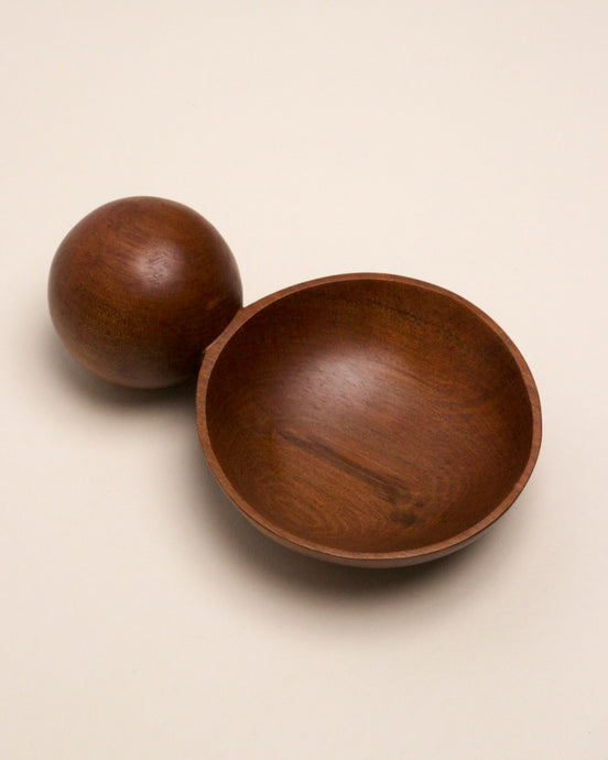 A hand carved spoon made of miro on a white back ground, the spoon bowl is deep and round and the handle is a hand carved sphere.