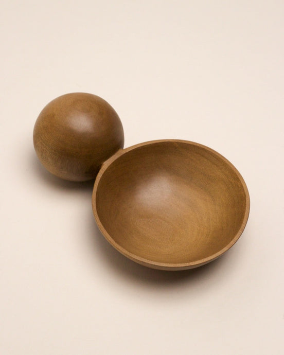 A hand carved spoon made of kauri on a white back ground, the spoon bowl is deep and round and the handle is a hand carved sphere.