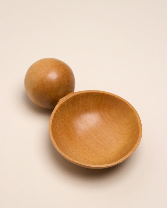 A hand carved spoon made of kauri on a white back ground, the spoon bowl is deep and round and the handle is a hand carved sphere.