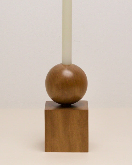 Hand-carved candle holder made from kauri wood, featuring a spherical base atop a square block.
