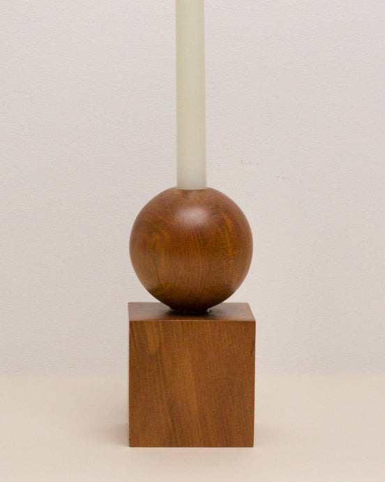 Hand-carved candle holder made from kauri wood, featuring a spherical base atop a square block.