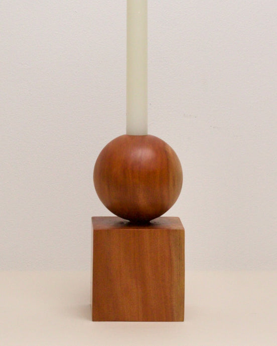 Hand-carved candle holder made from Tōtara wood, featuring a spherical base atop a square block.